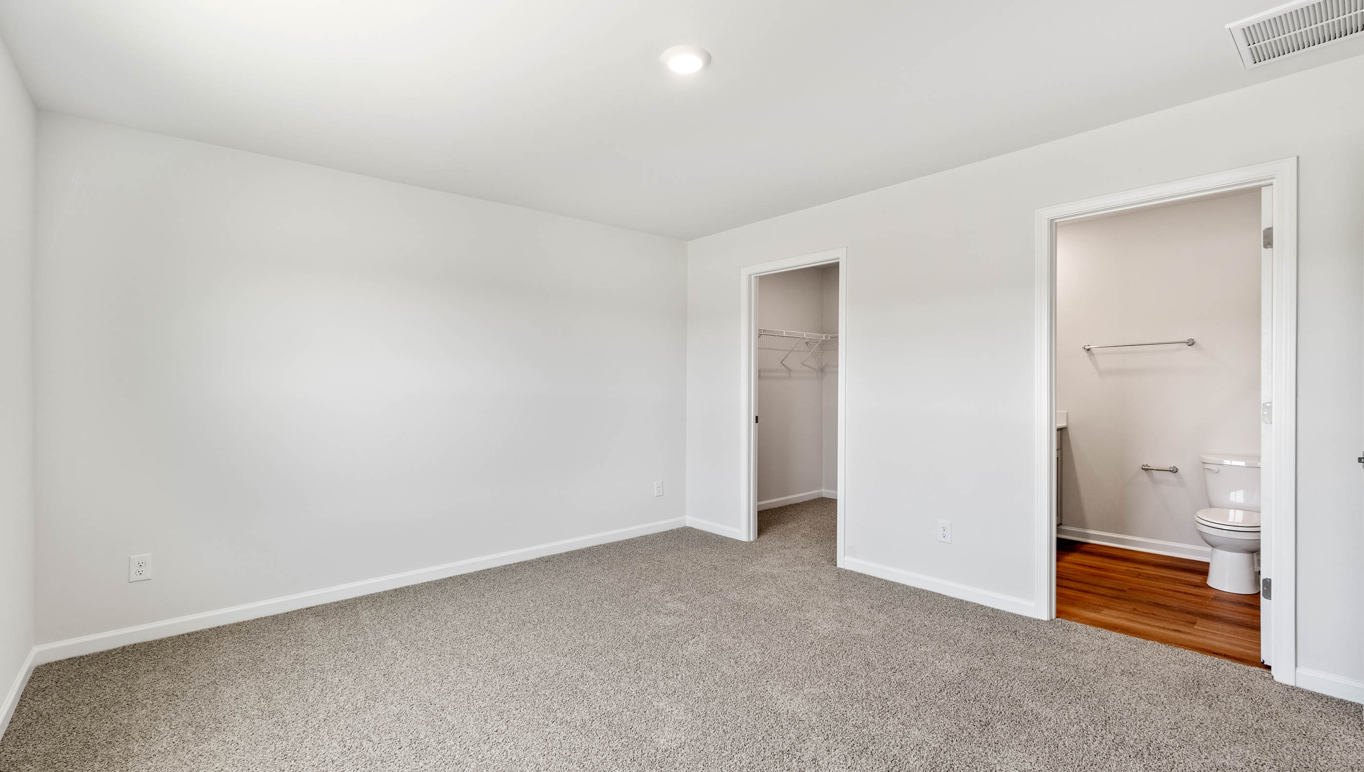 Primary bedroom with window and carpet.