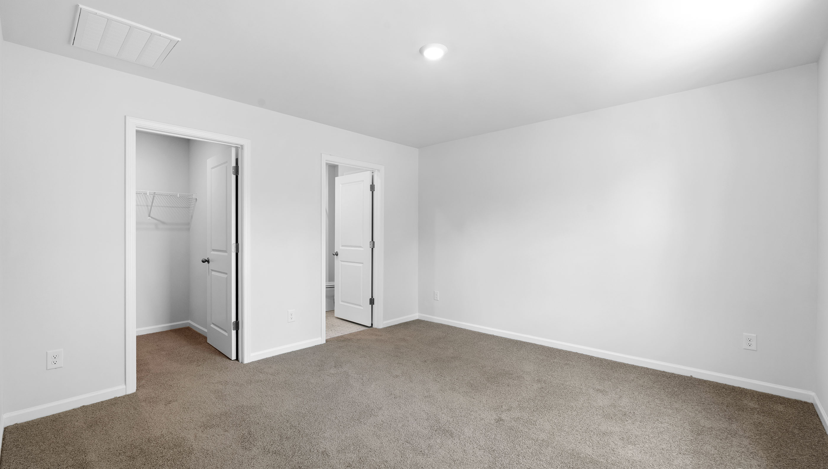 Primary bedroom with carpet and window.