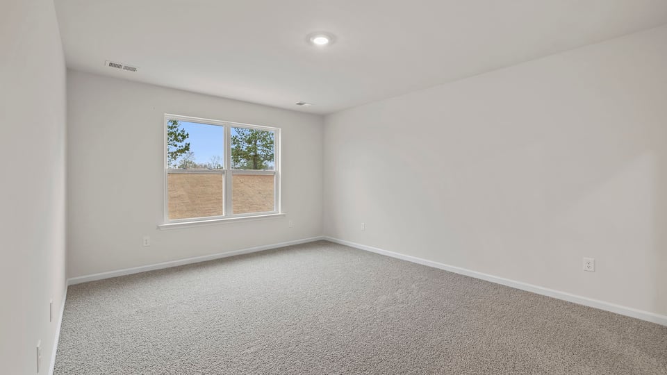 Primary bedroom with window and carpet.