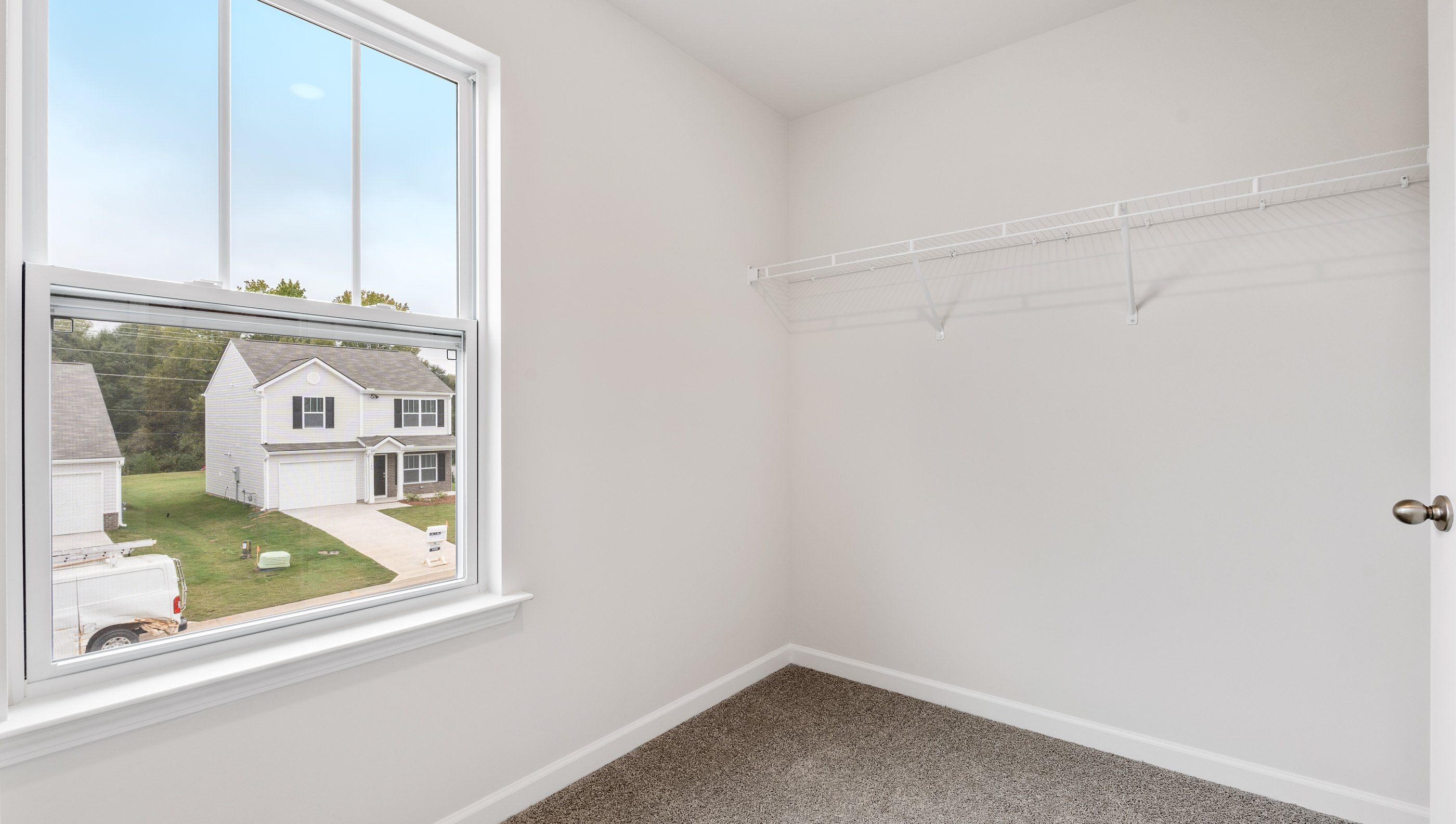 Primary closet with carpet and window.