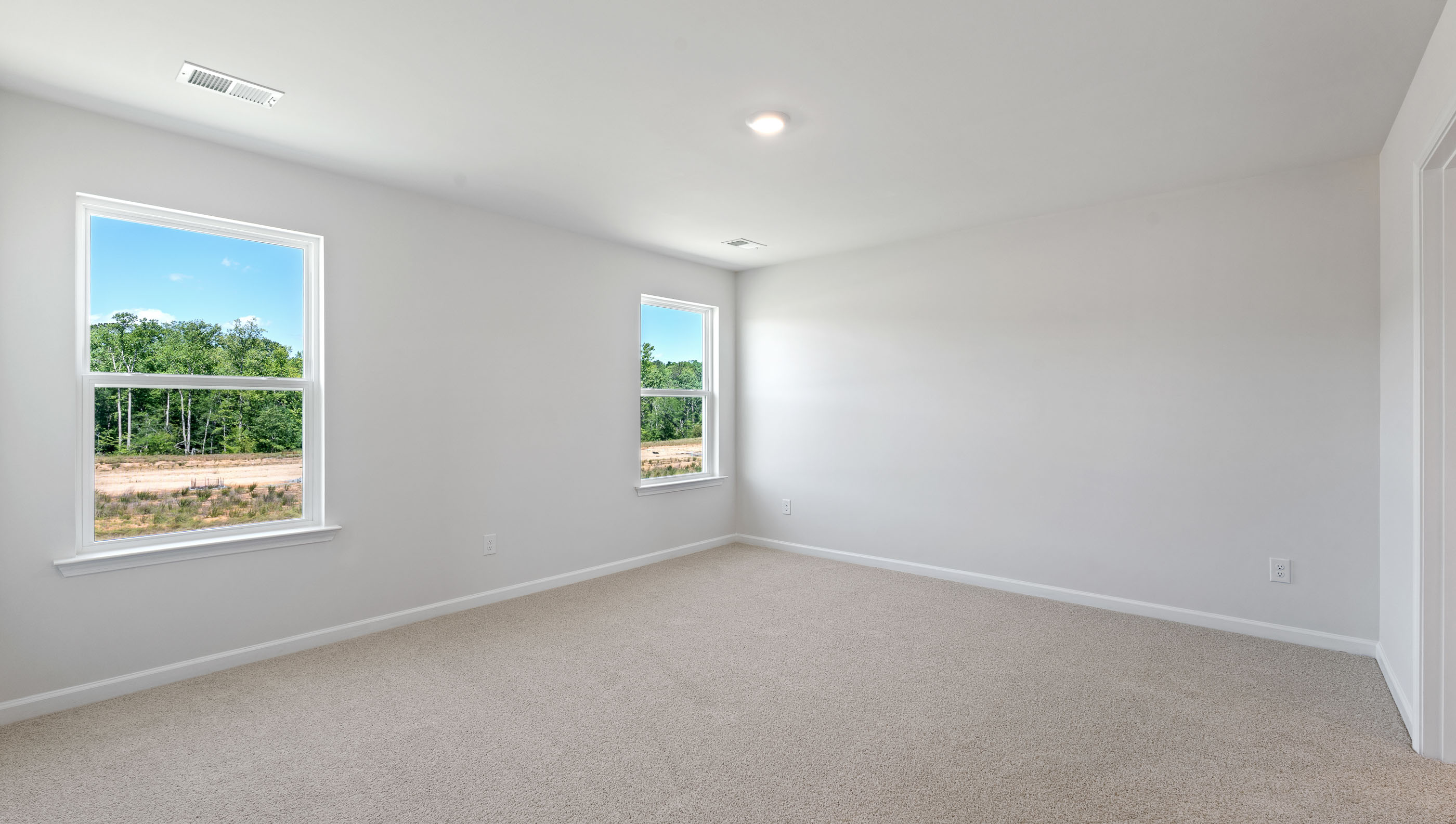 Primary bedroom with windows and carpet.