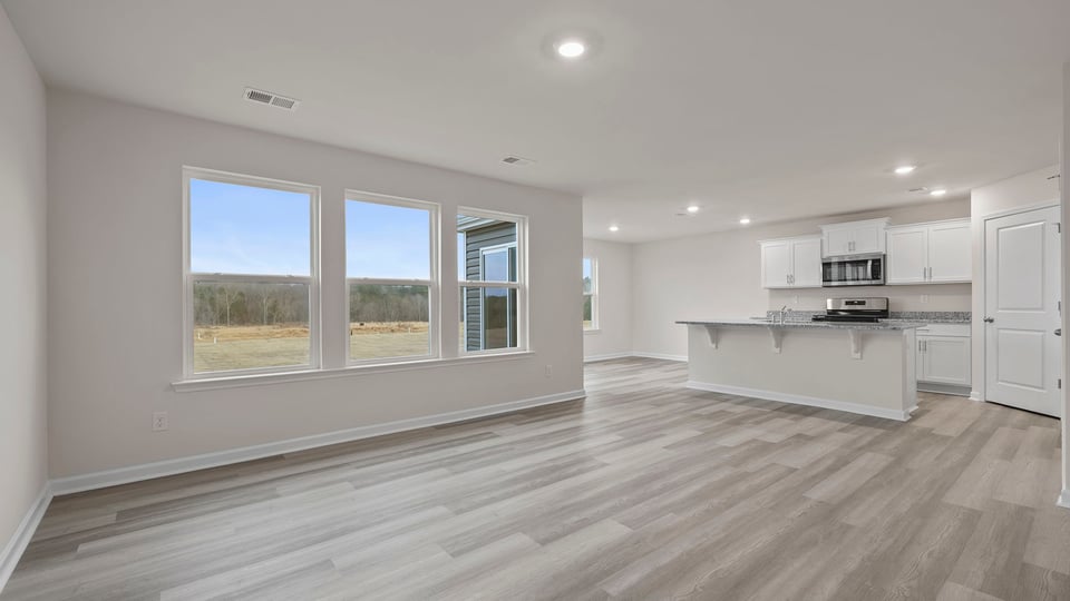 View of open floorplan including family room, kitchen, and dining area.