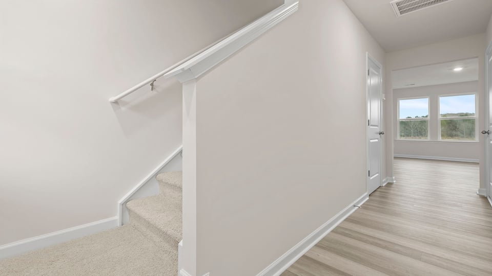 Entrance with view of stairwell and wall of windows in the family room.