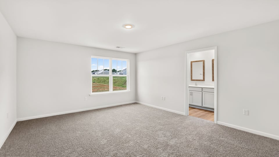 Primary bedroom with carpet and windows.