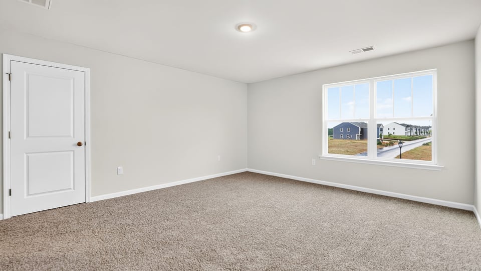 Primary bedroom with carpet and windows.