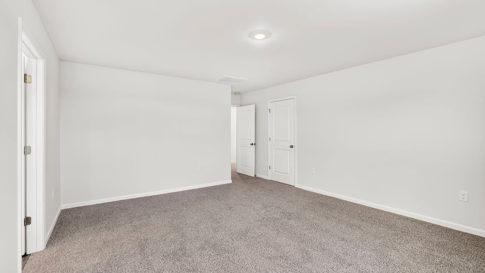 Primary bedroom with carpet and windows.