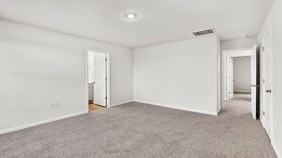 Primary bedroom with carpet and windows.