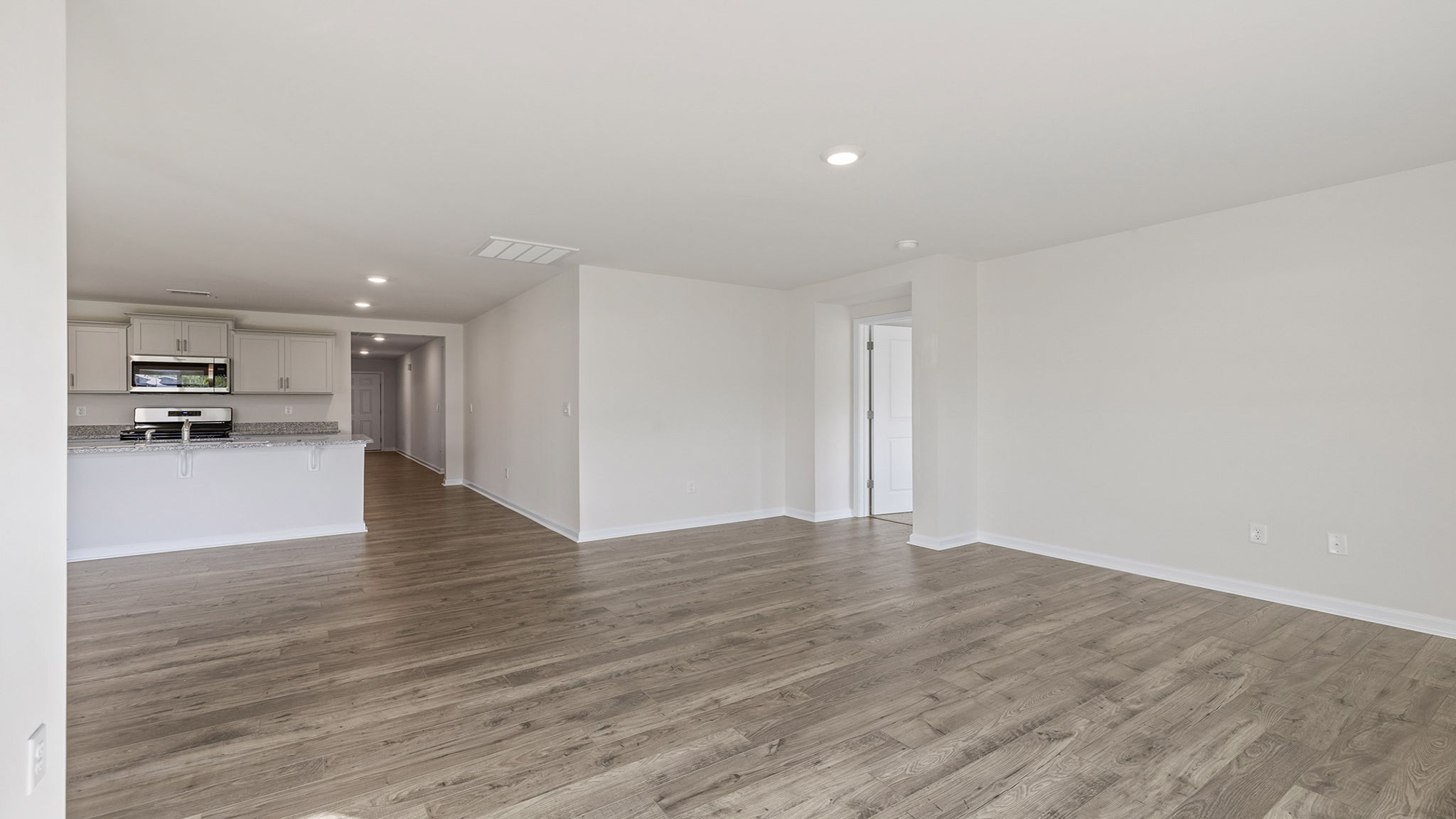 View of family room toward the kitchen with view of hallway to the entrance.