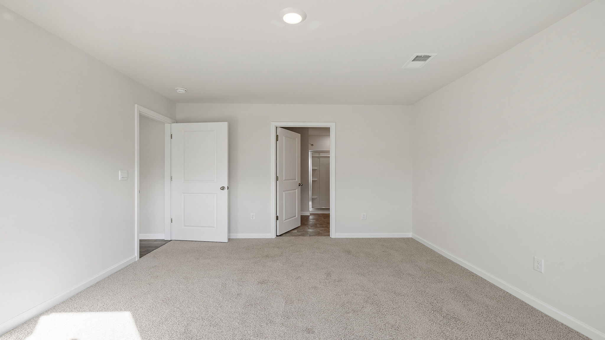 Primary bedroom with large window and carpet.