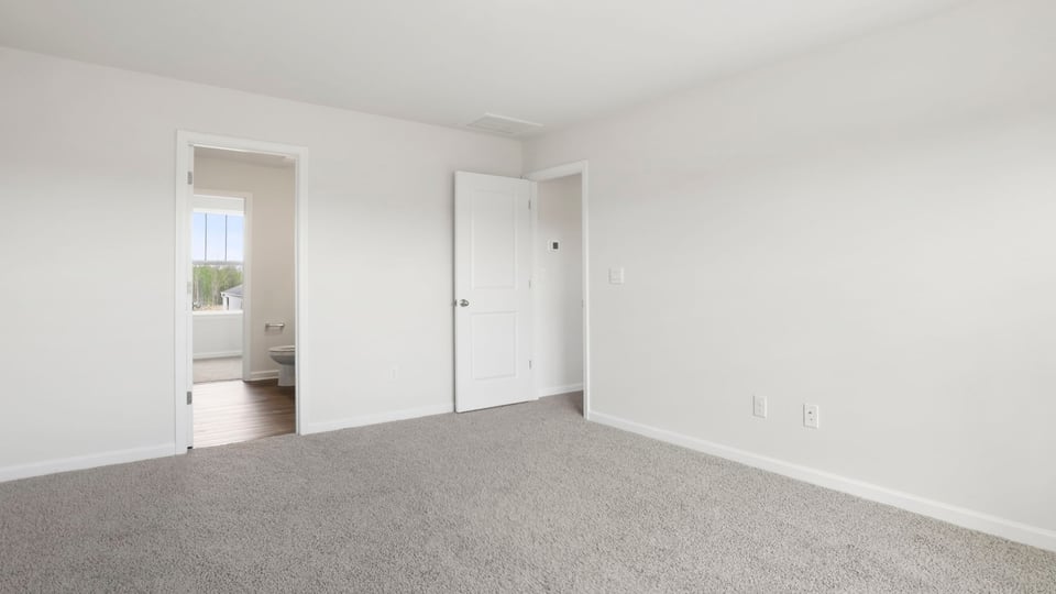 Primary bedroom with carpet and windows.