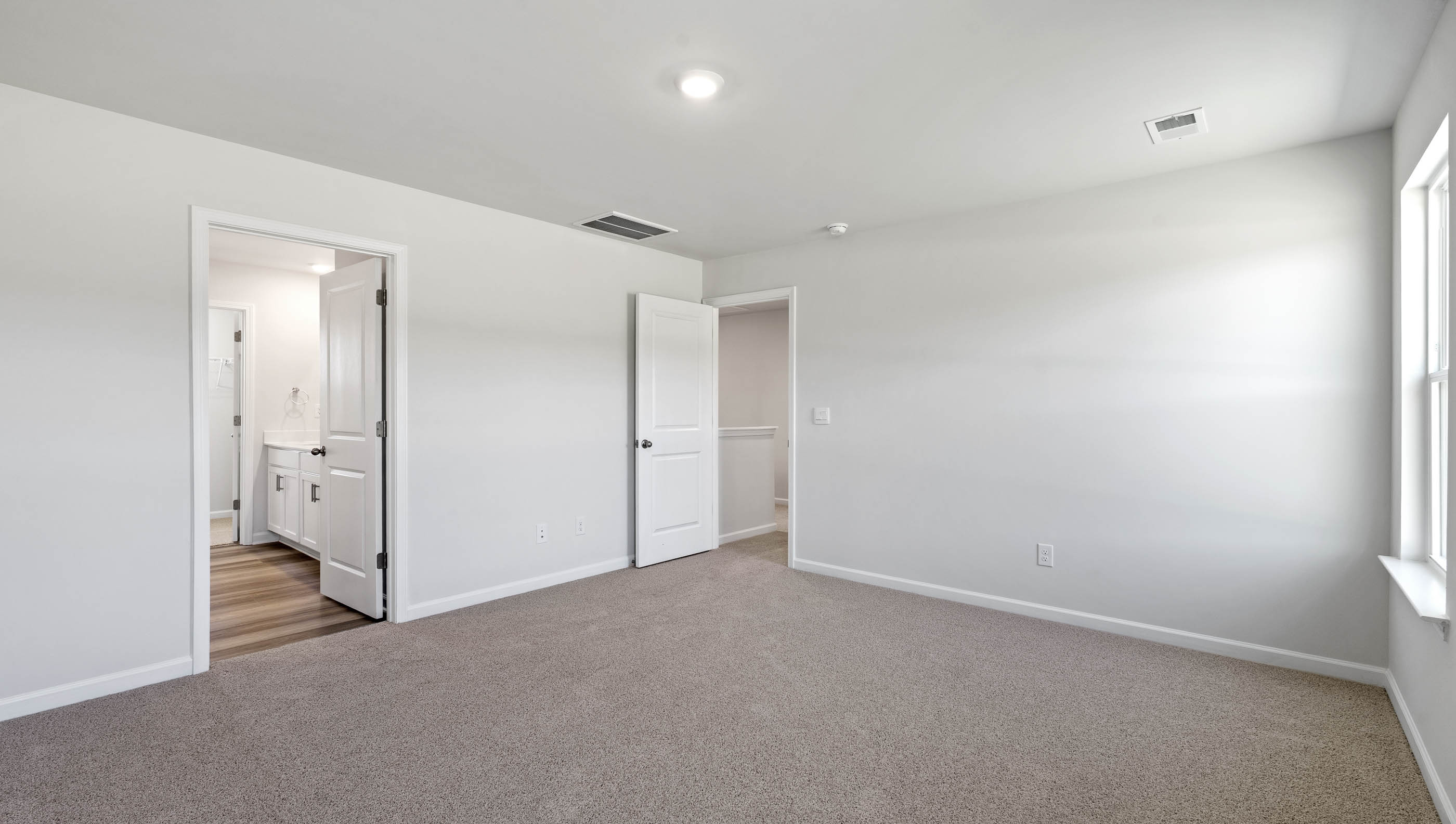Primary bedroom with carpet and windows.
