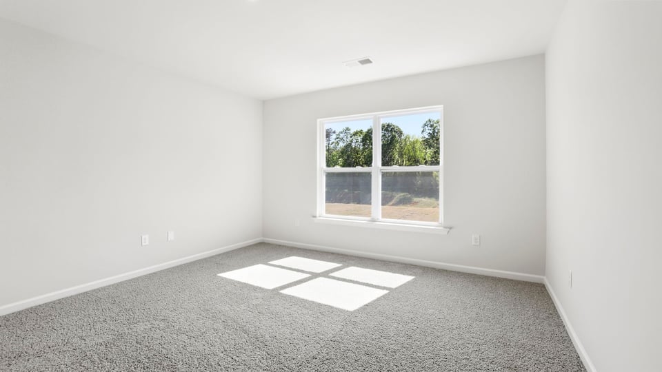 Primary bedroom with carpet and windows.