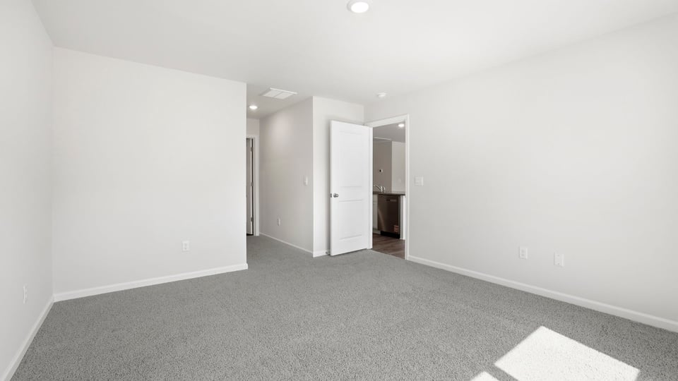 Primary bedroom with carpet and windows.