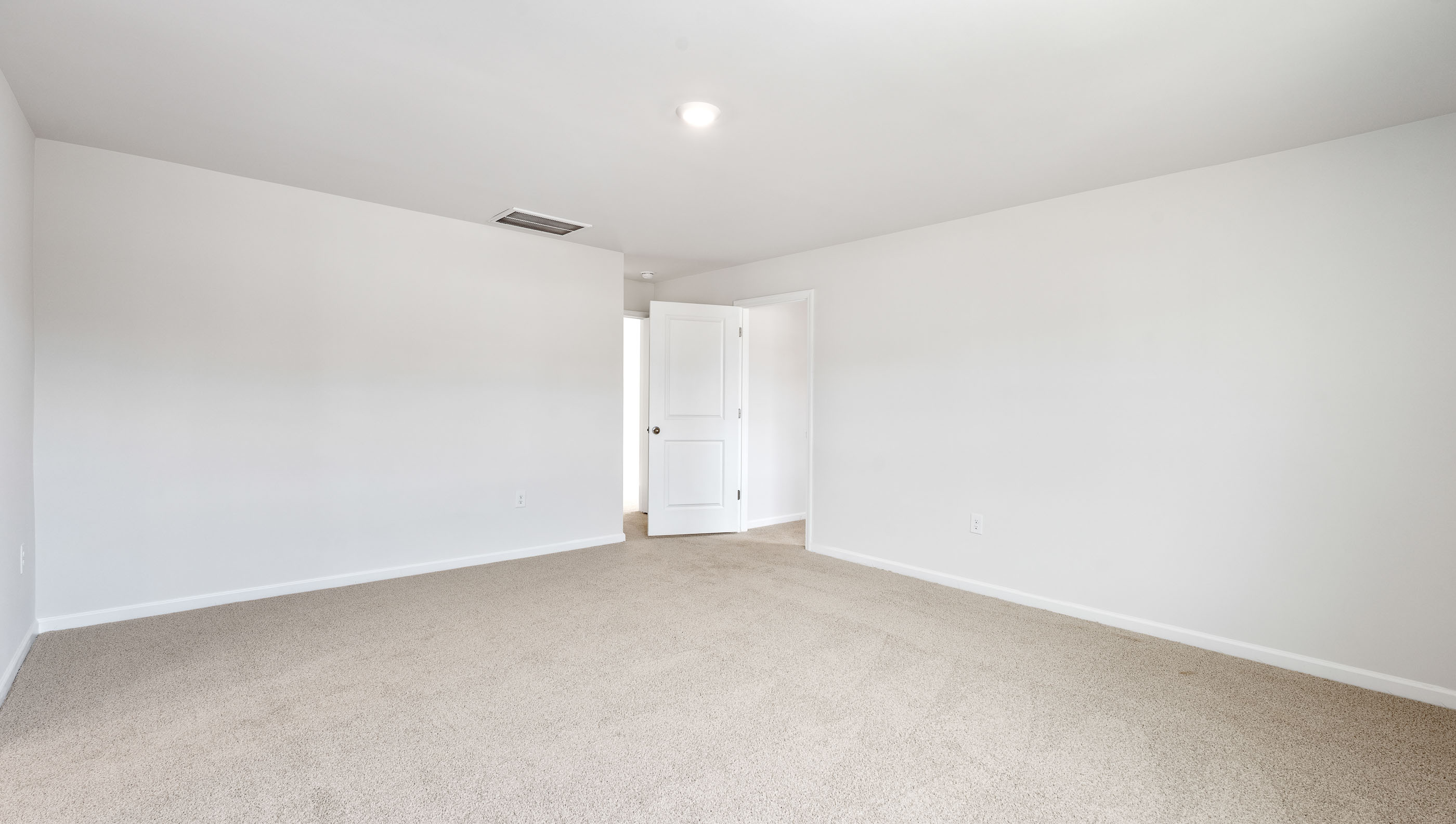 Primary bedroom with carpet and window.