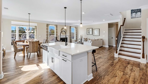 Kitchen and island with stairs and view of family room.
