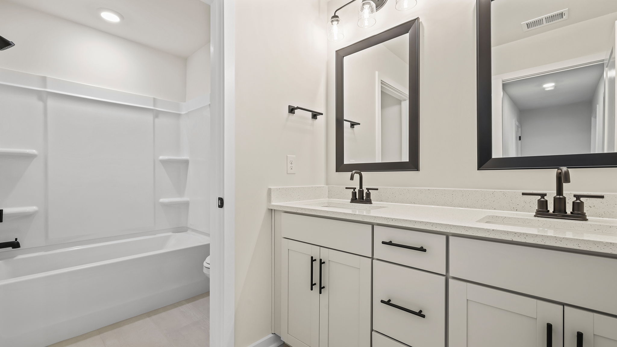 Hall bathroom with dual sink vanity and combination shower / tub.
