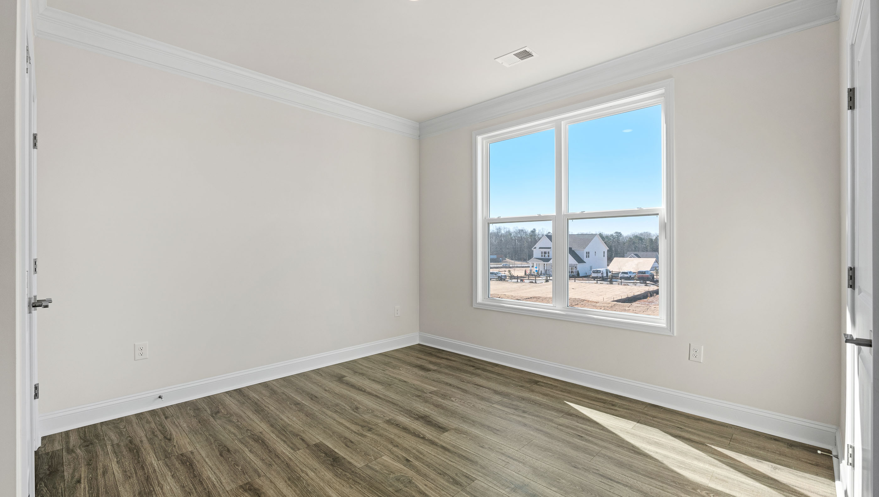 Bedroom with redwood flooring and windows.
