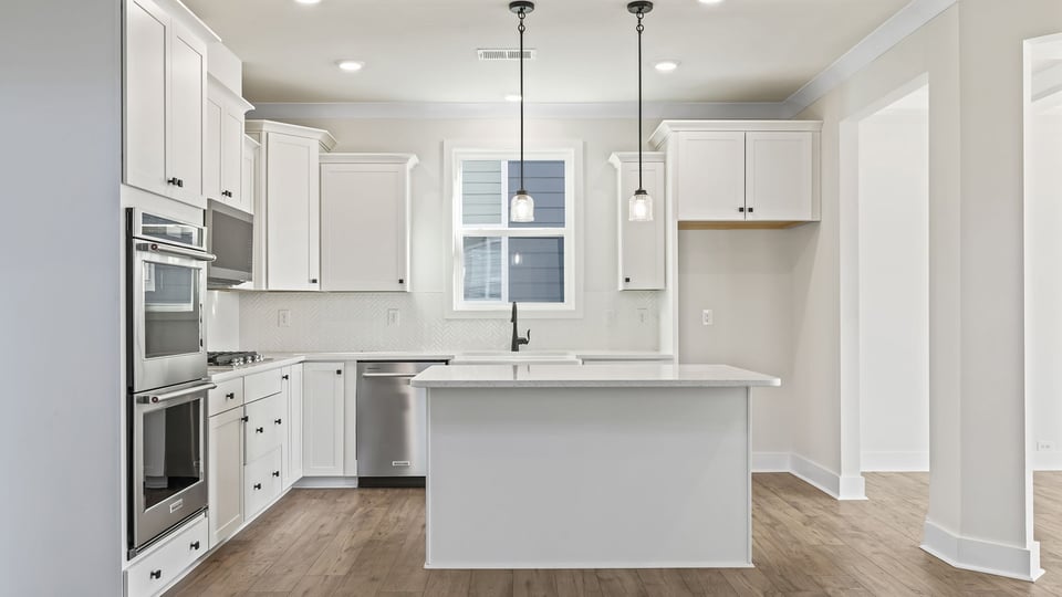 Gourmet kitchen with island and pendulum lighting.