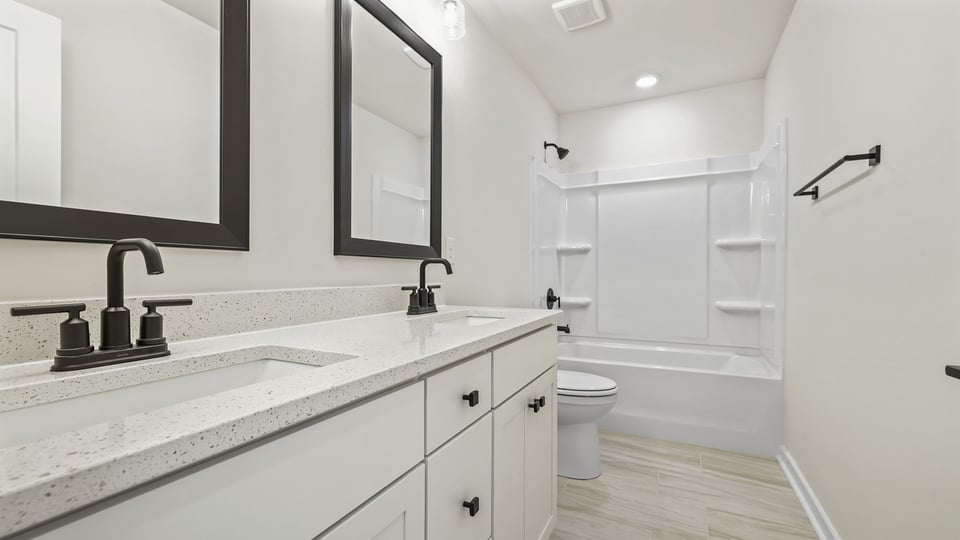 Hall bathroom with dual sink vanity and combination shower / tub.