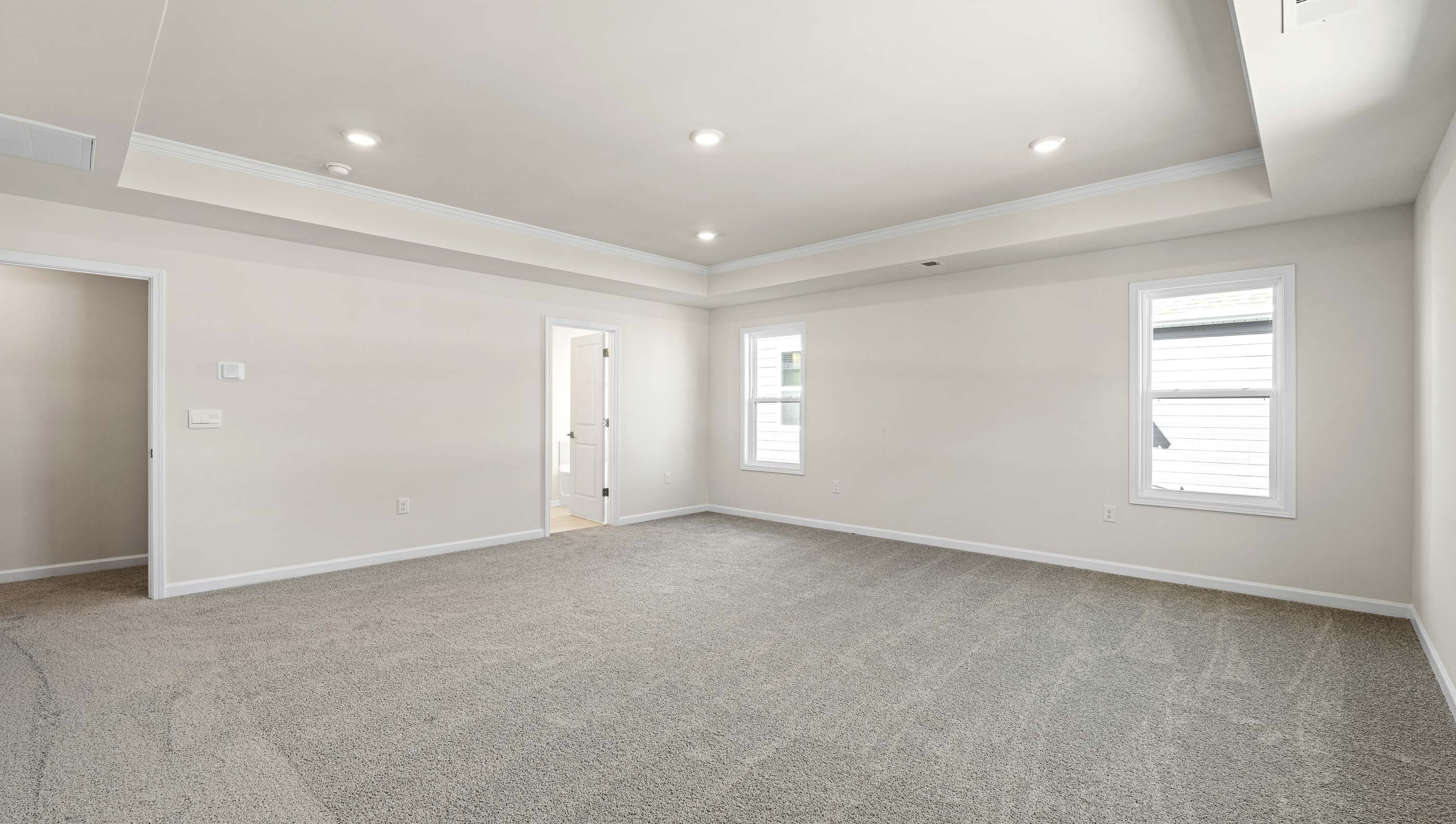 Primary bedroom with carpet and windows.