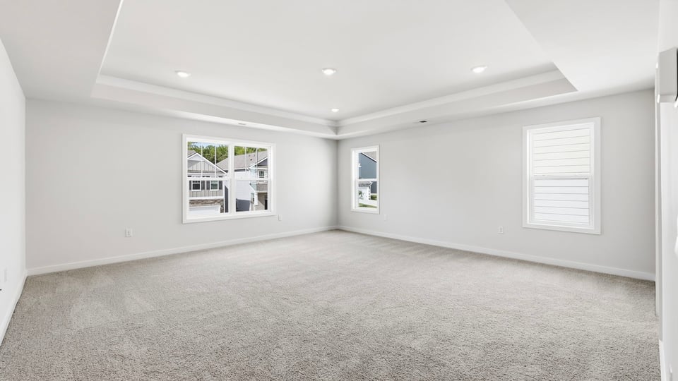 Primary bedroom with carpet and windows.