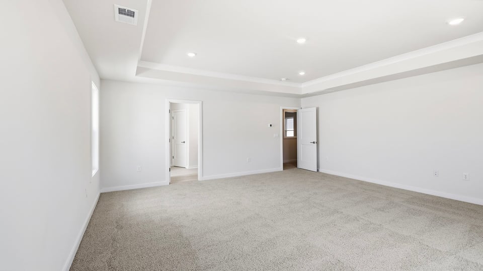 Primary bedroom with carpet and windows.