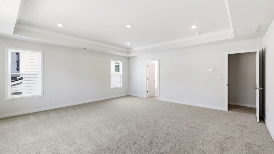 Primary bedroom with carpet and windows.