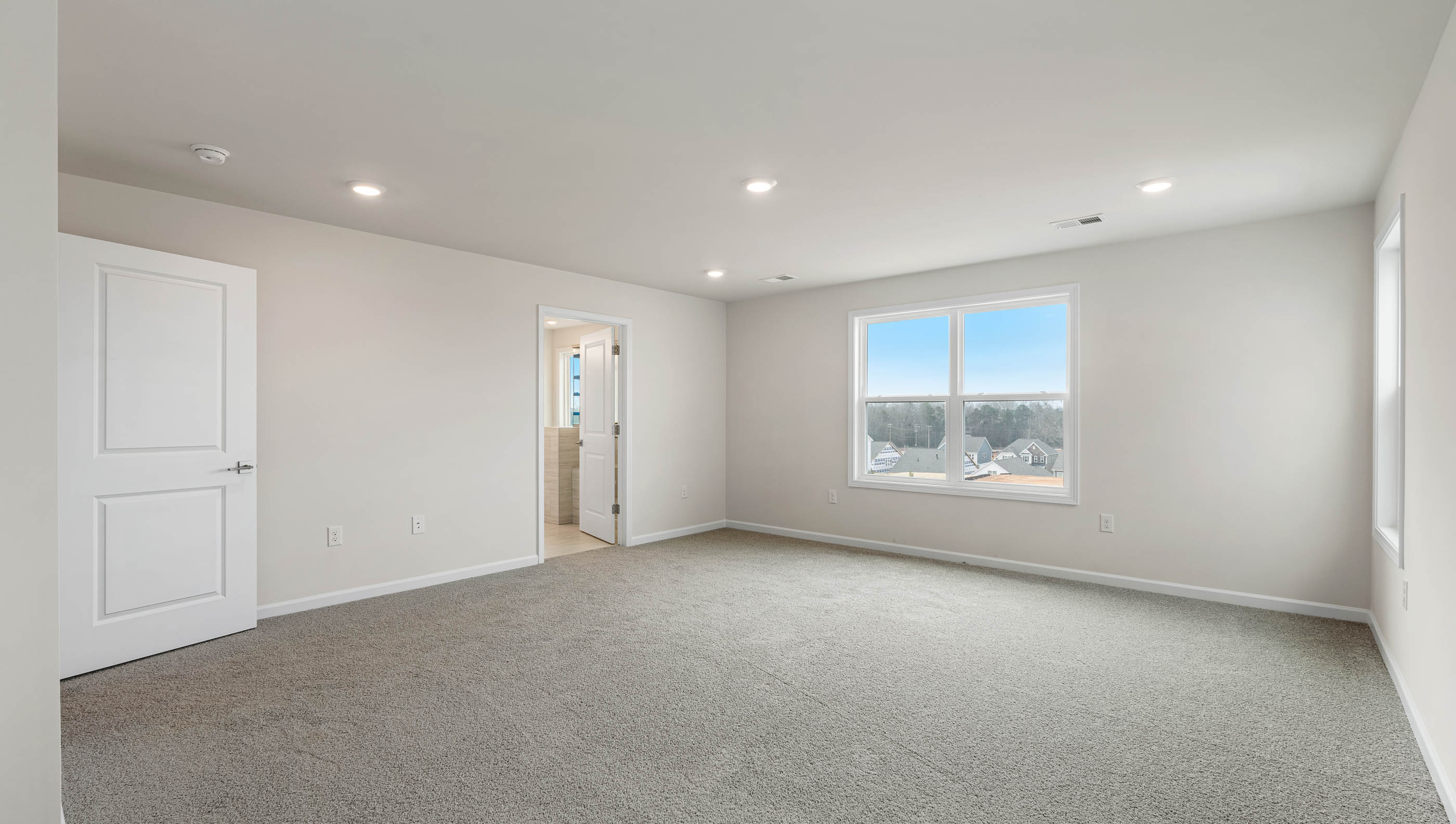 Primary bedroom with carpet and window.