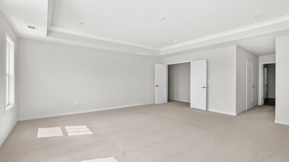 Primary bedroom with carpet and window.