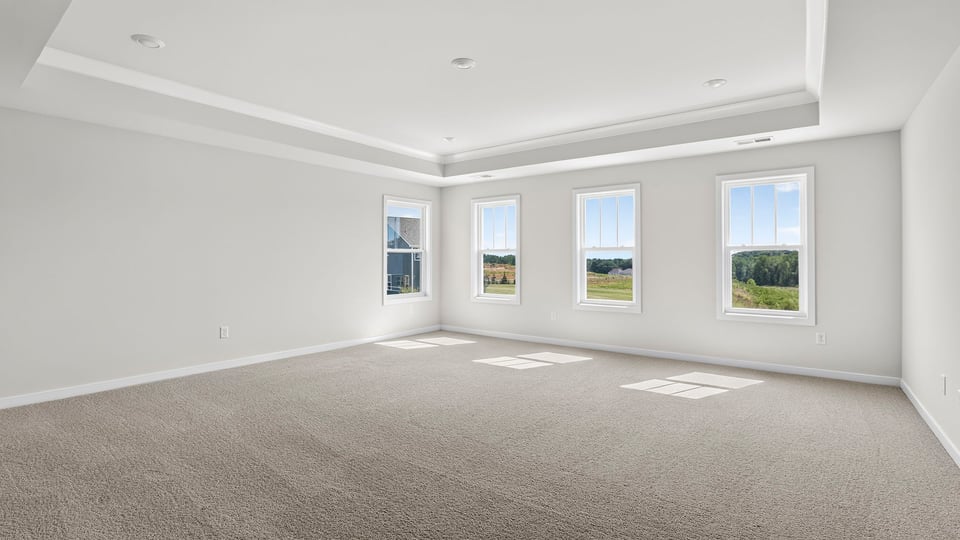 Primary bedroom with carpet and window.