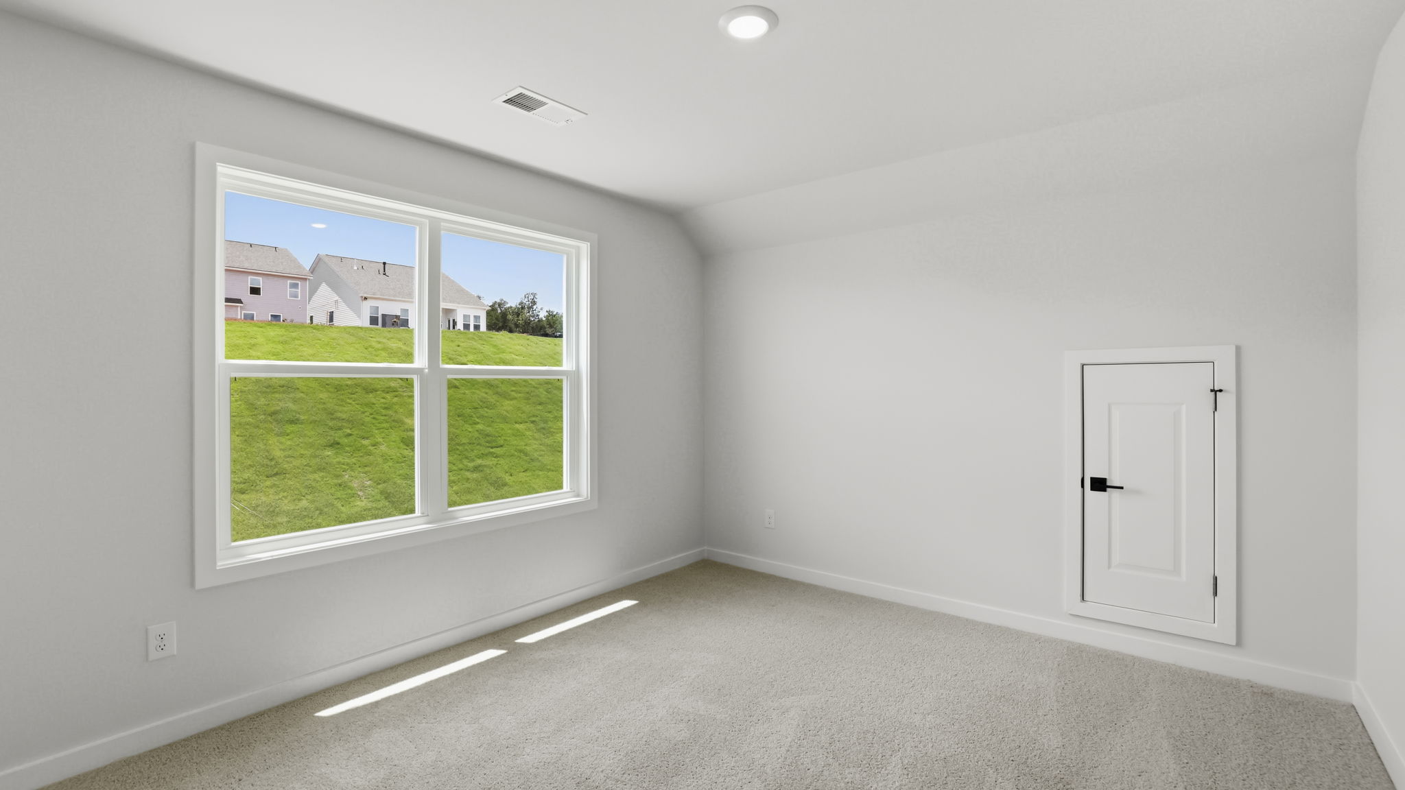 Primary bedroom with carpet and windows.