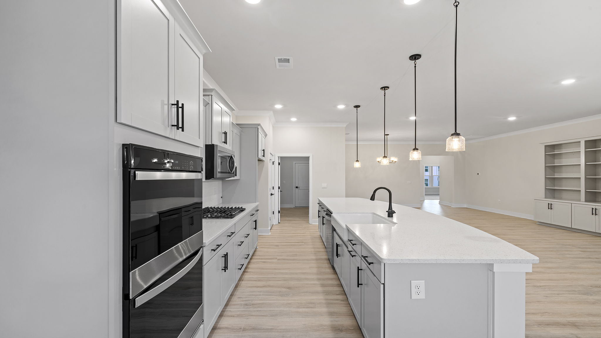 Gourmet kitchen with quartz countertop island and pendulum lighting.