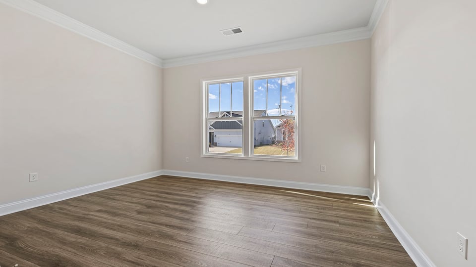 Bedroom with large window and laminate flooring.