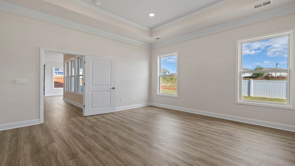 Primary bedroom with lots of windows and laminate flooring.