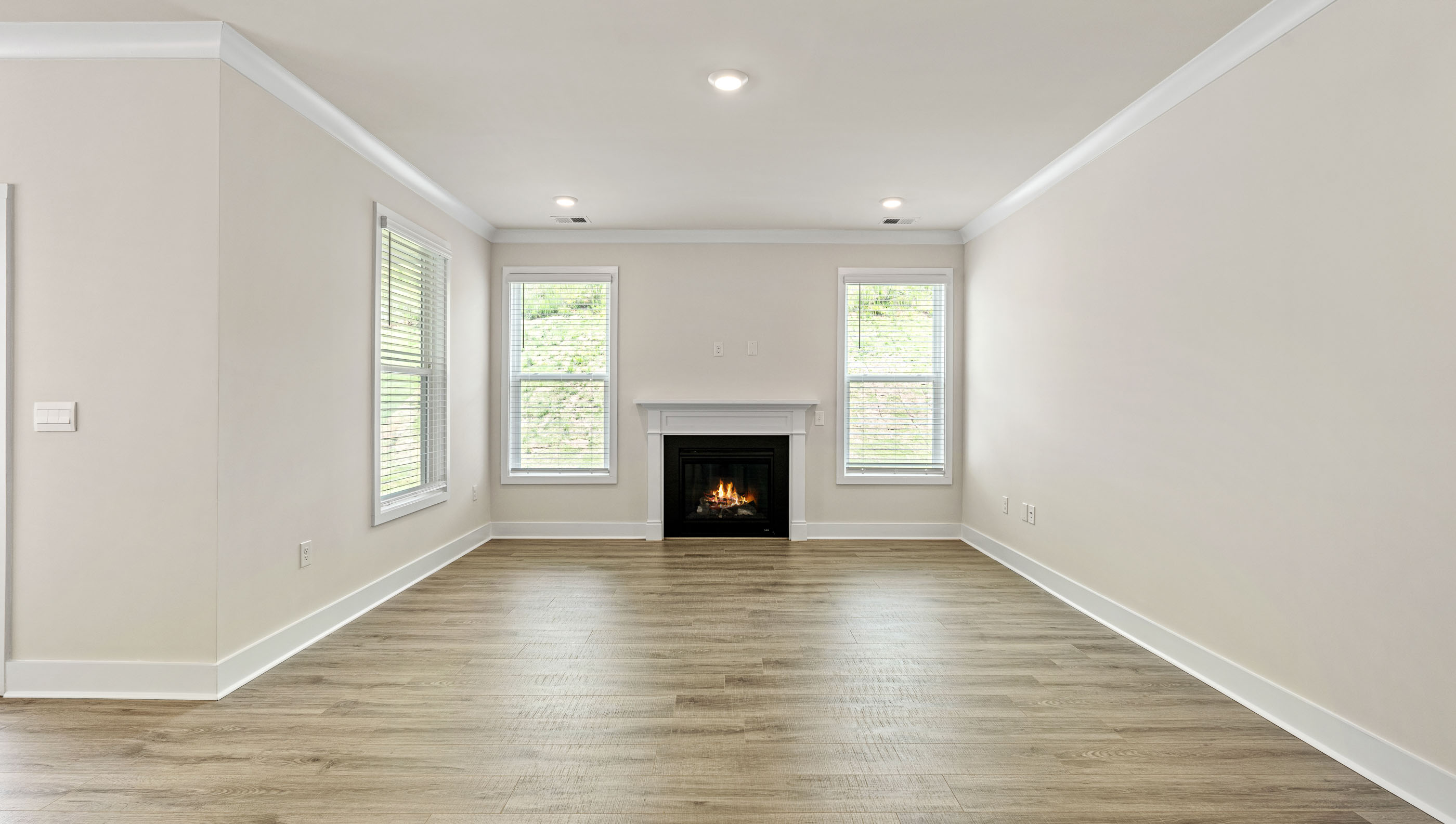 Family room with gas log fireplace accented by two windows.
