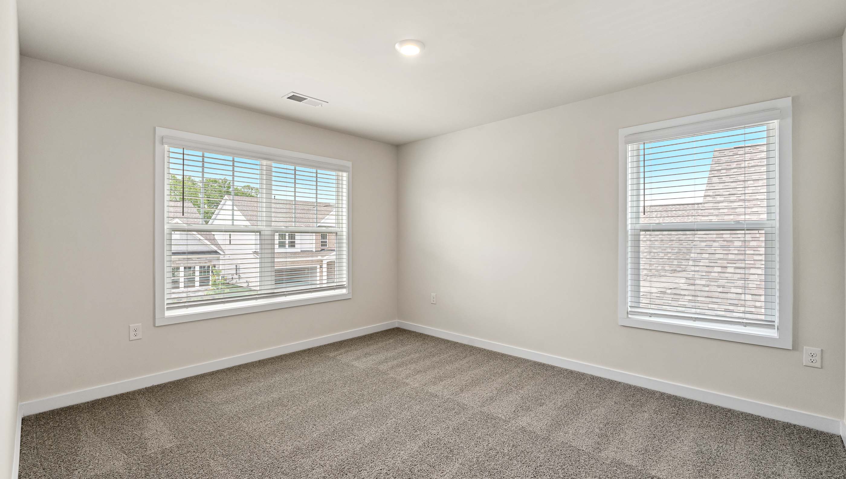 Bedroom with two large windows and carpet.
