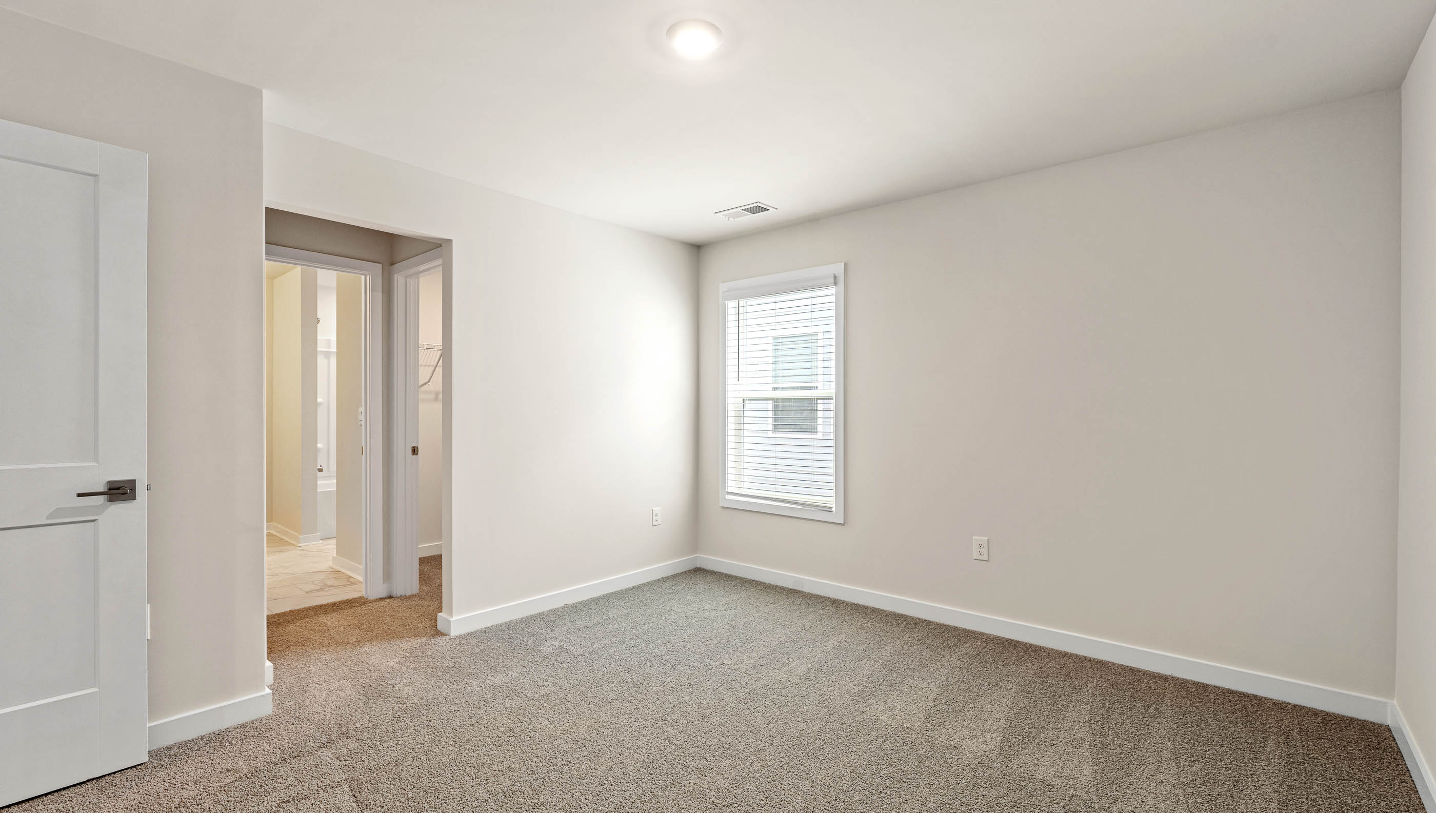 Bedroom with large window and carpet.