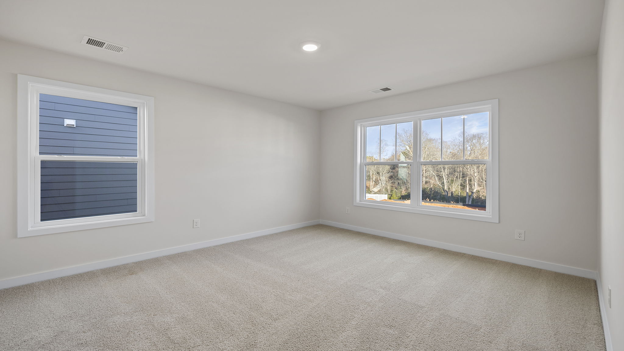 Bedroom with two large windows and carpet.