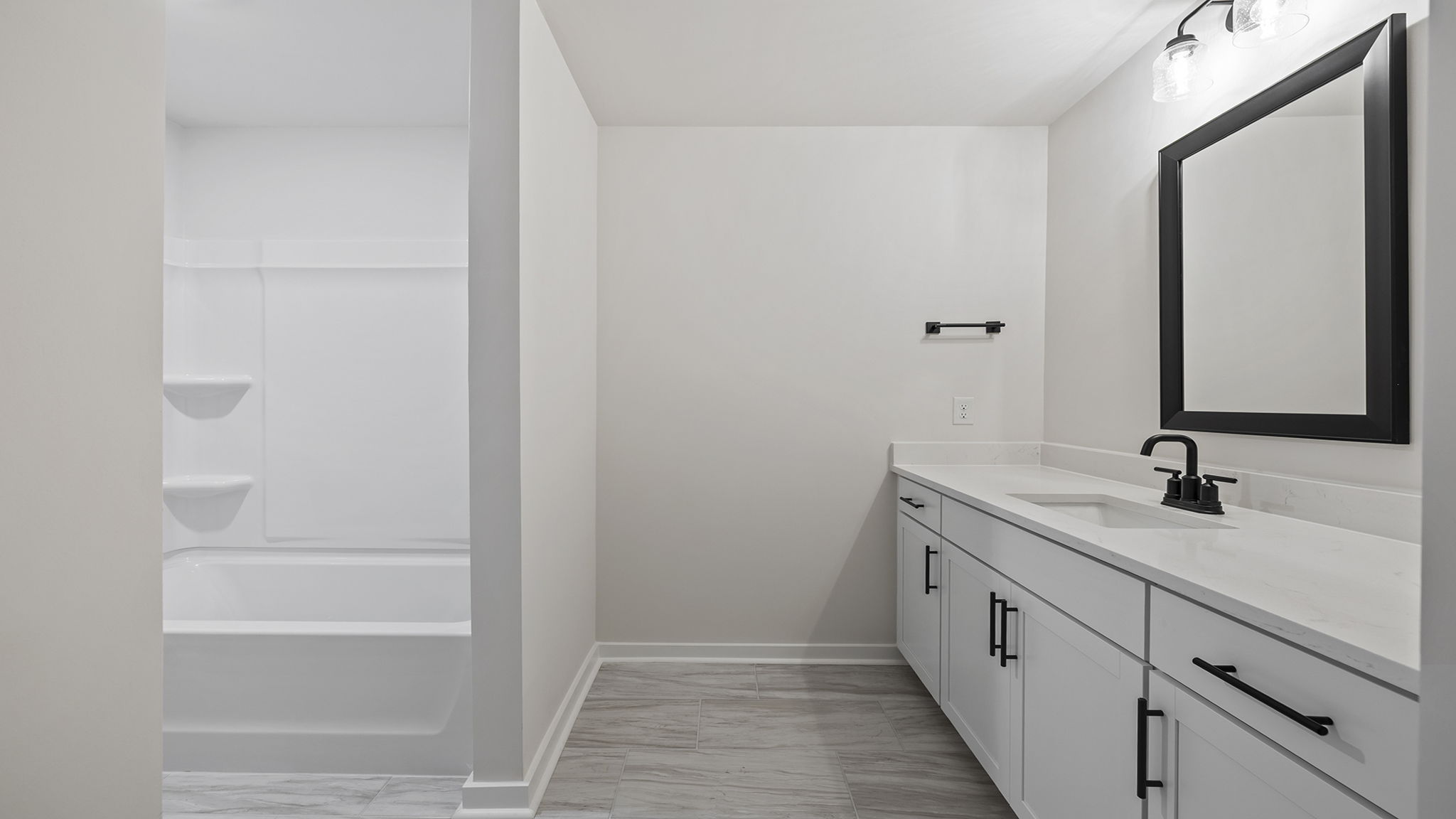 Hall bathroom with dual sink vanity and combination shower / tub.