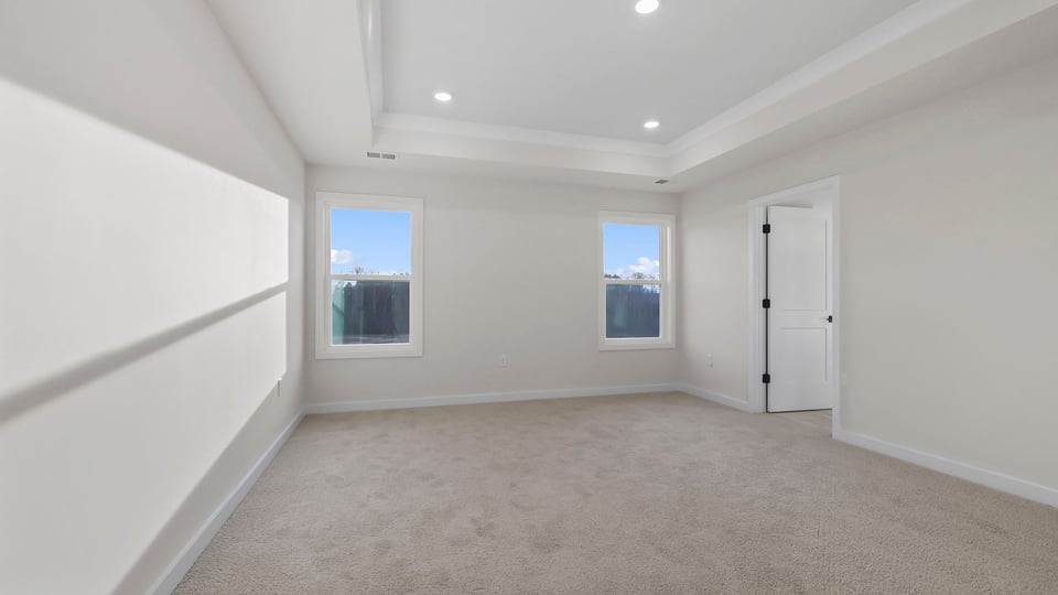 Primary bedroom with carpet and windows.