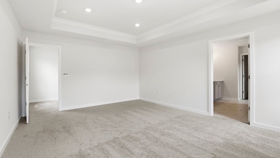 Primary bedroom with carpet and windows.