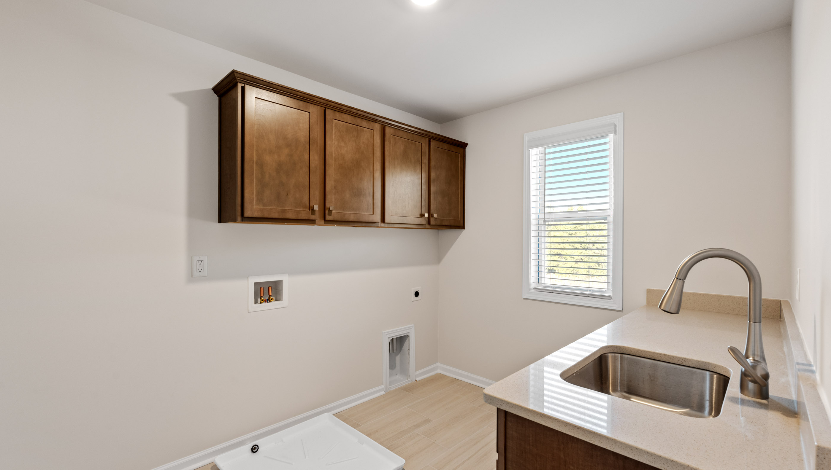 Walk-in laundry room with sink and cabinets.