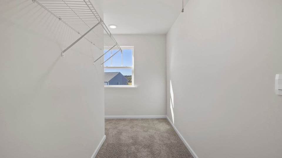 Walk in closet with shelves and window.