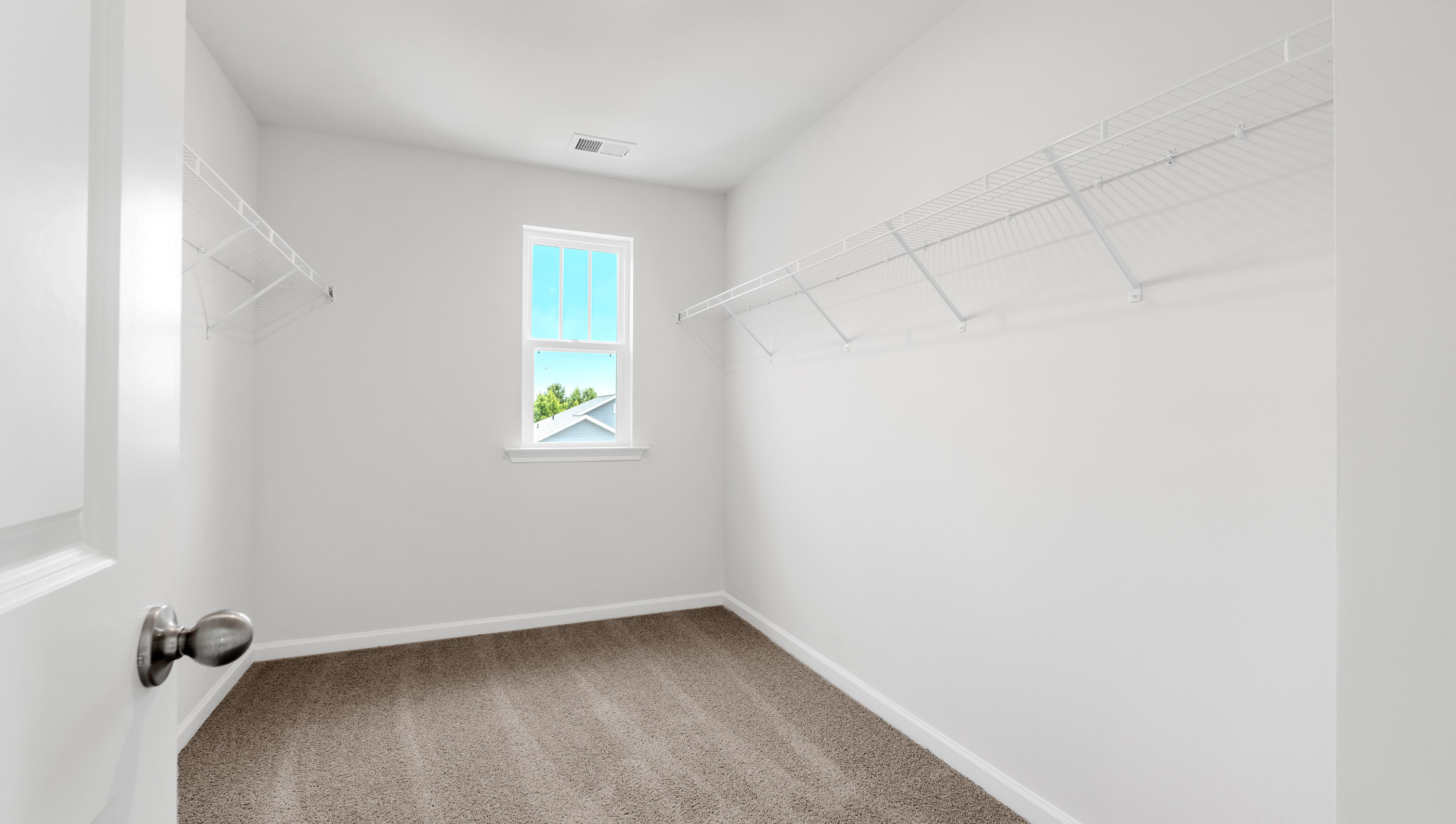 Walk in closet with hanging shelves and window.
