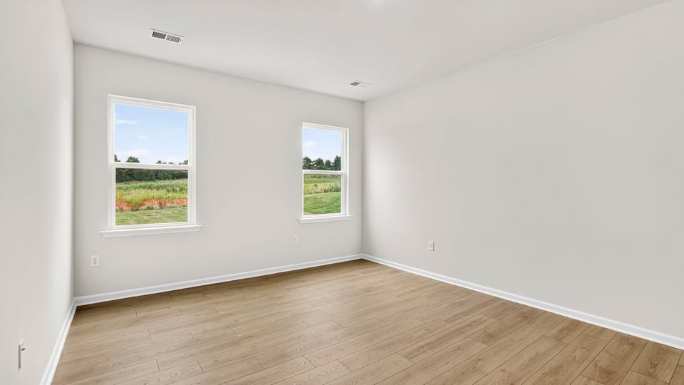 Primary bedroom with hardwood floors and window