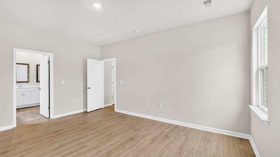Primary bedroom with hardwood floors and closet/doorway