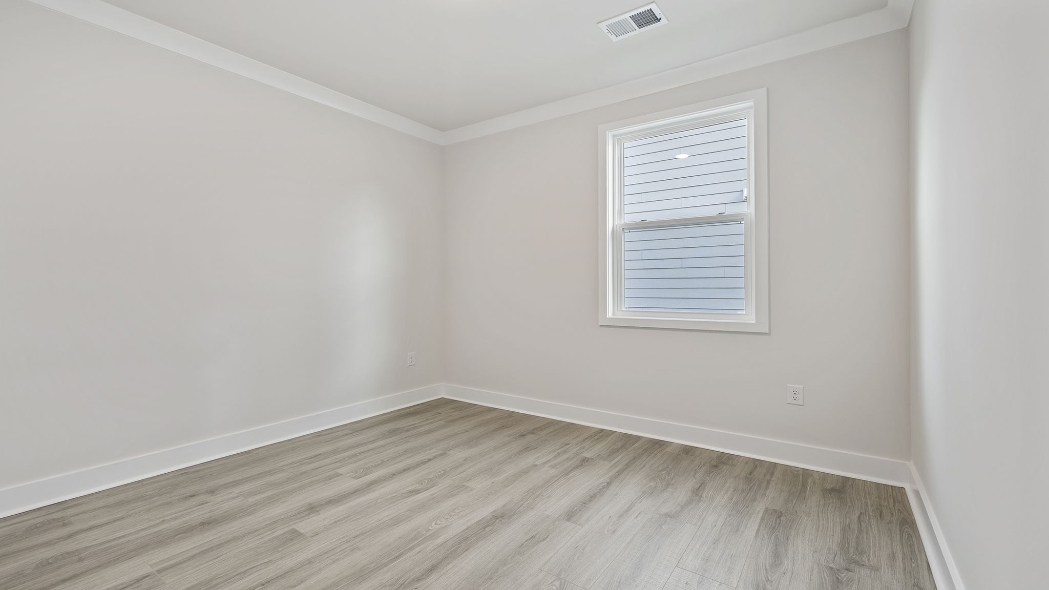 Bedroom with large windows and laminate flooring.