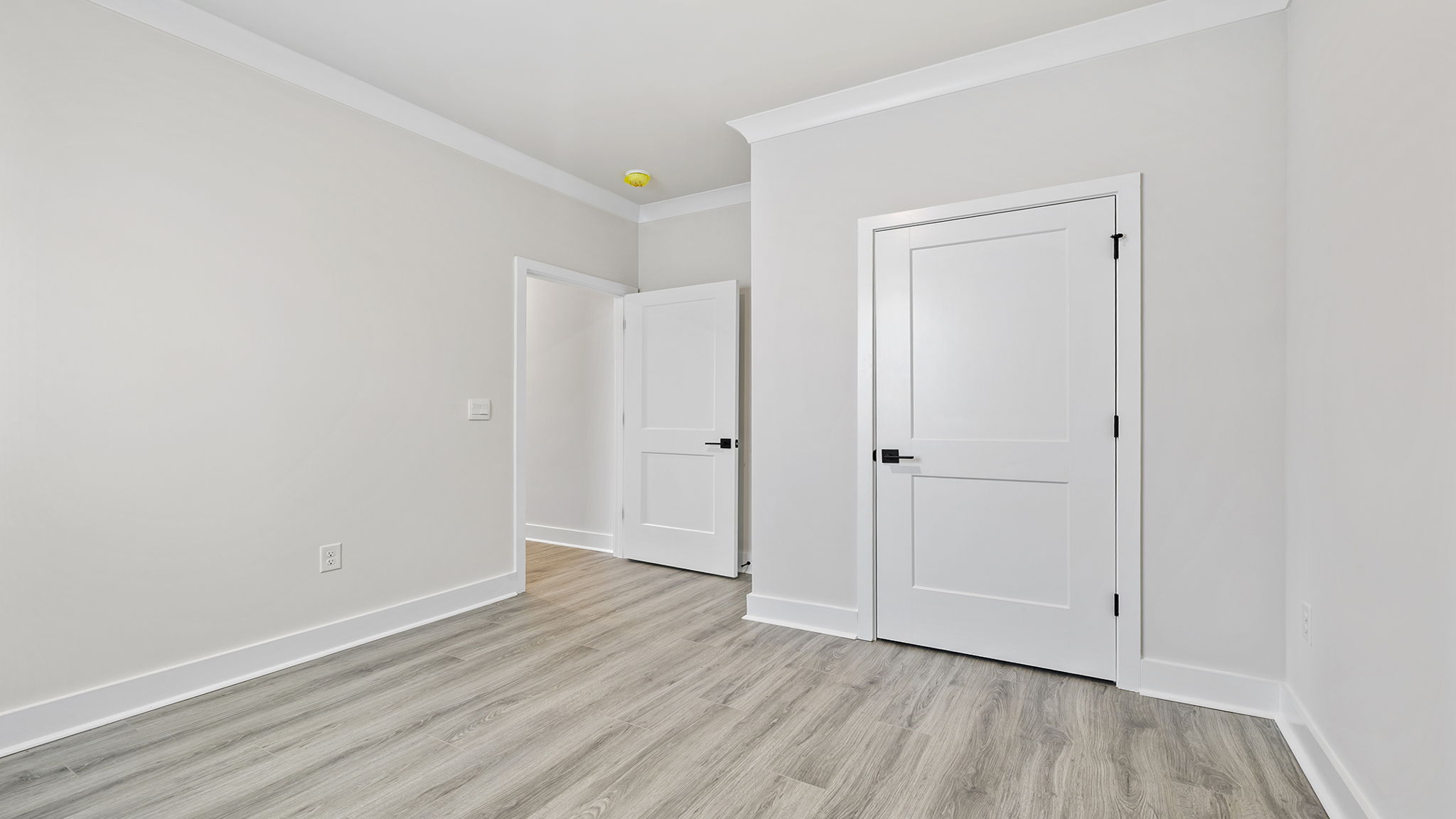 Bedroom with large windows and laminate flooring.