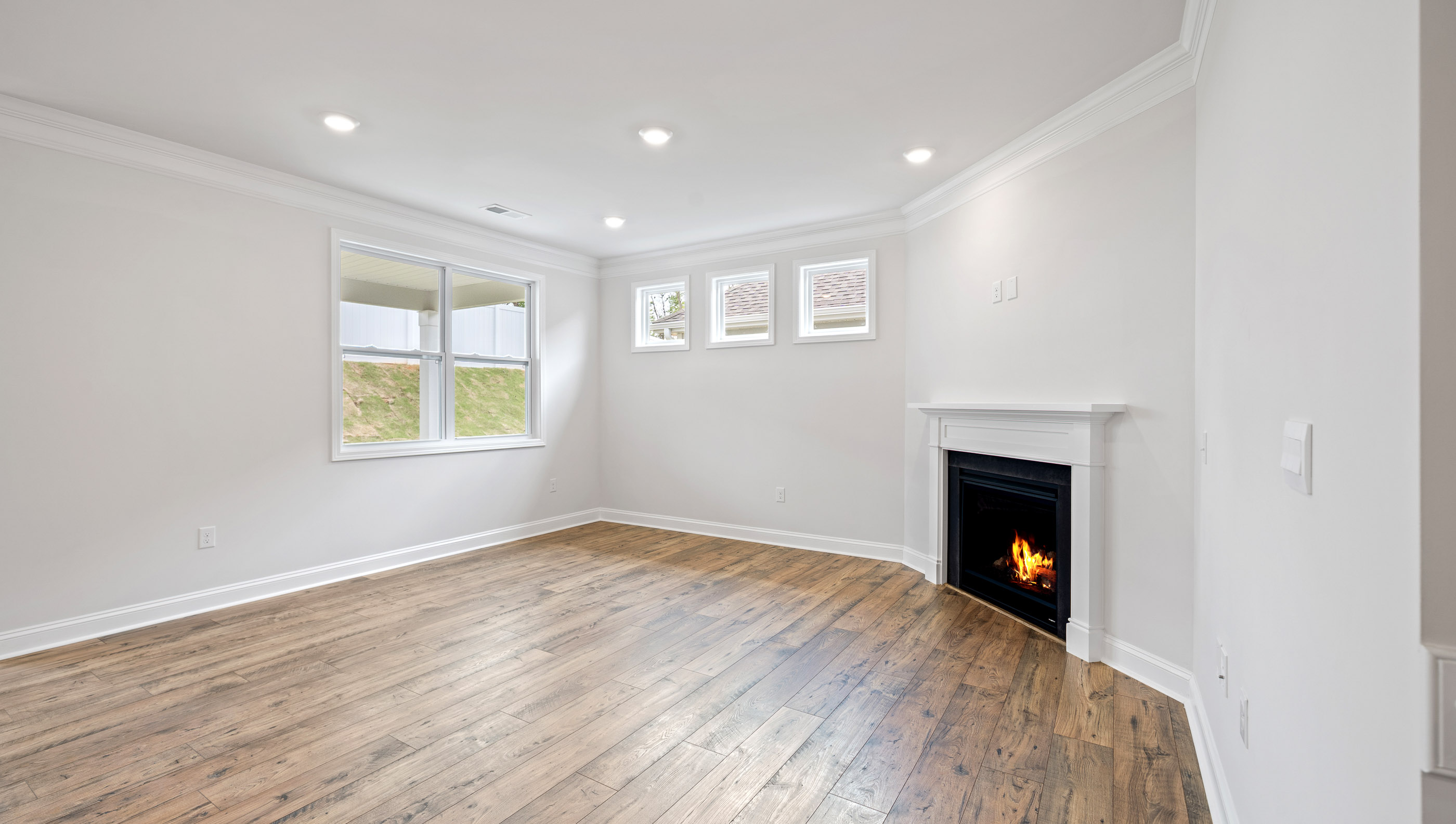 Family room with recessed lighting, windows and gas log fireplace.