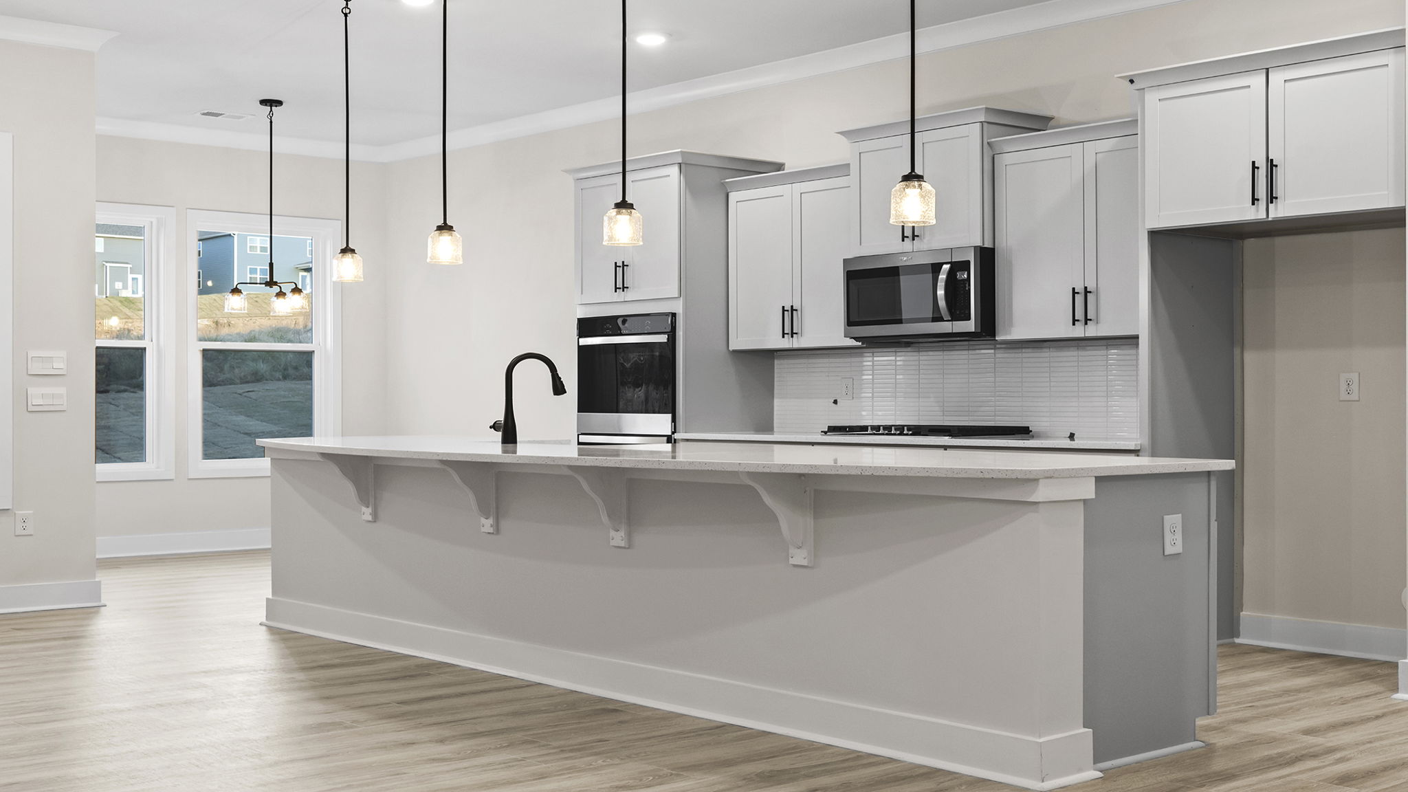 Open kitchen with large island and pendulum lighting.